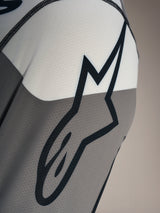 Dettaglio maglia Alpinestars A-Dura Race LS con logo Astars nero su tessuto mesh traspirante grigio e bianco.