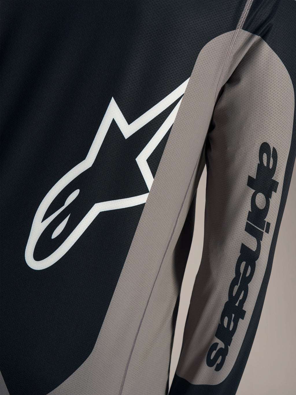 Maglia A-Dura Race grigia a maniche lunghe, logo Astars bianco sul petto e scritta Alpinestars sulla manica.