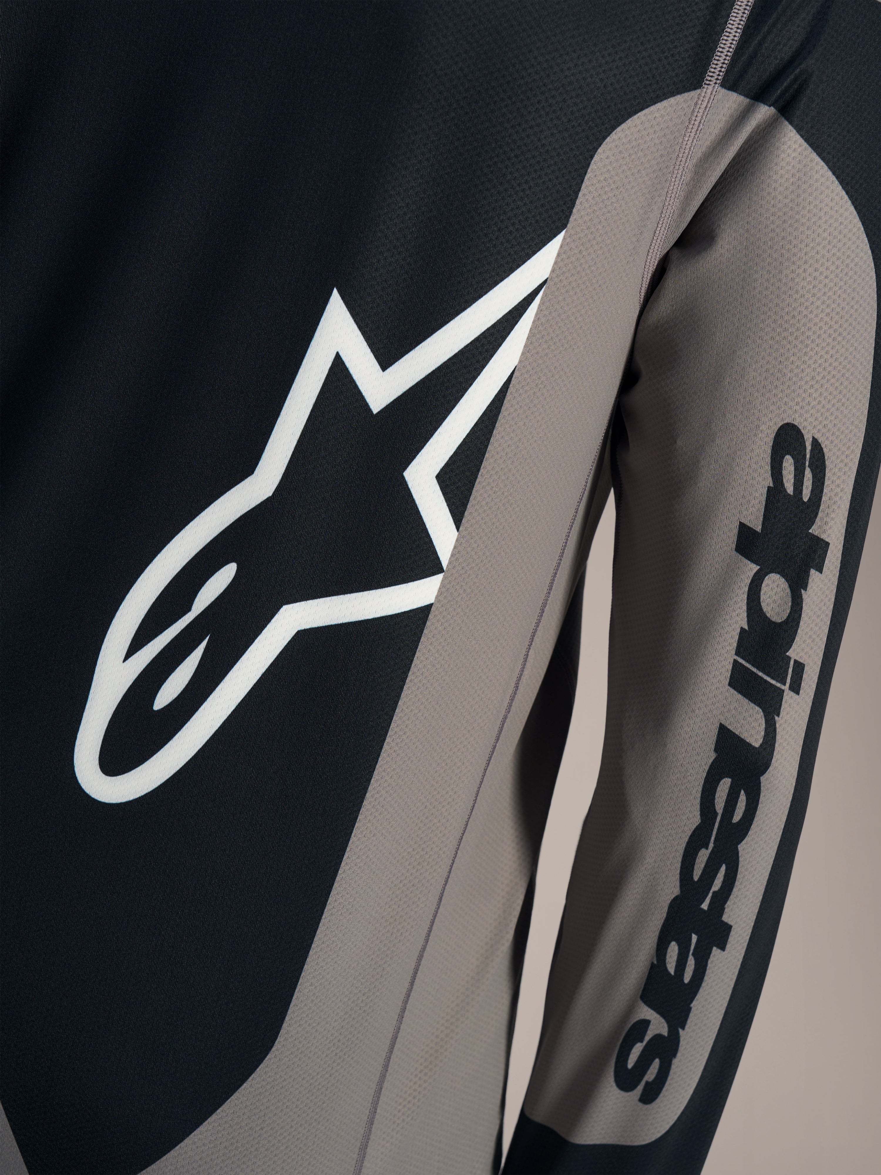 Maglia A-Dura Race grigia a maniche lunghe, logo Astars bianco sul petto e scritta Alpinestars sulla manica.