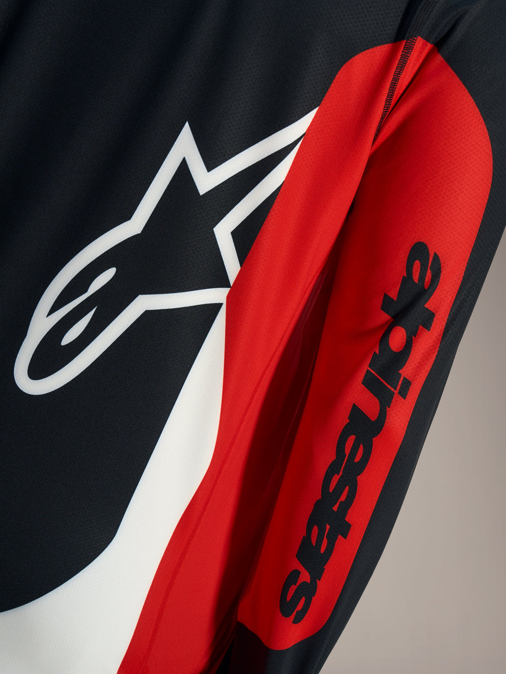 Dettaglio maglia A-Dura Race, logo Astars bianco e scritta nera su tessuto tecnico a rete rosso e nero.