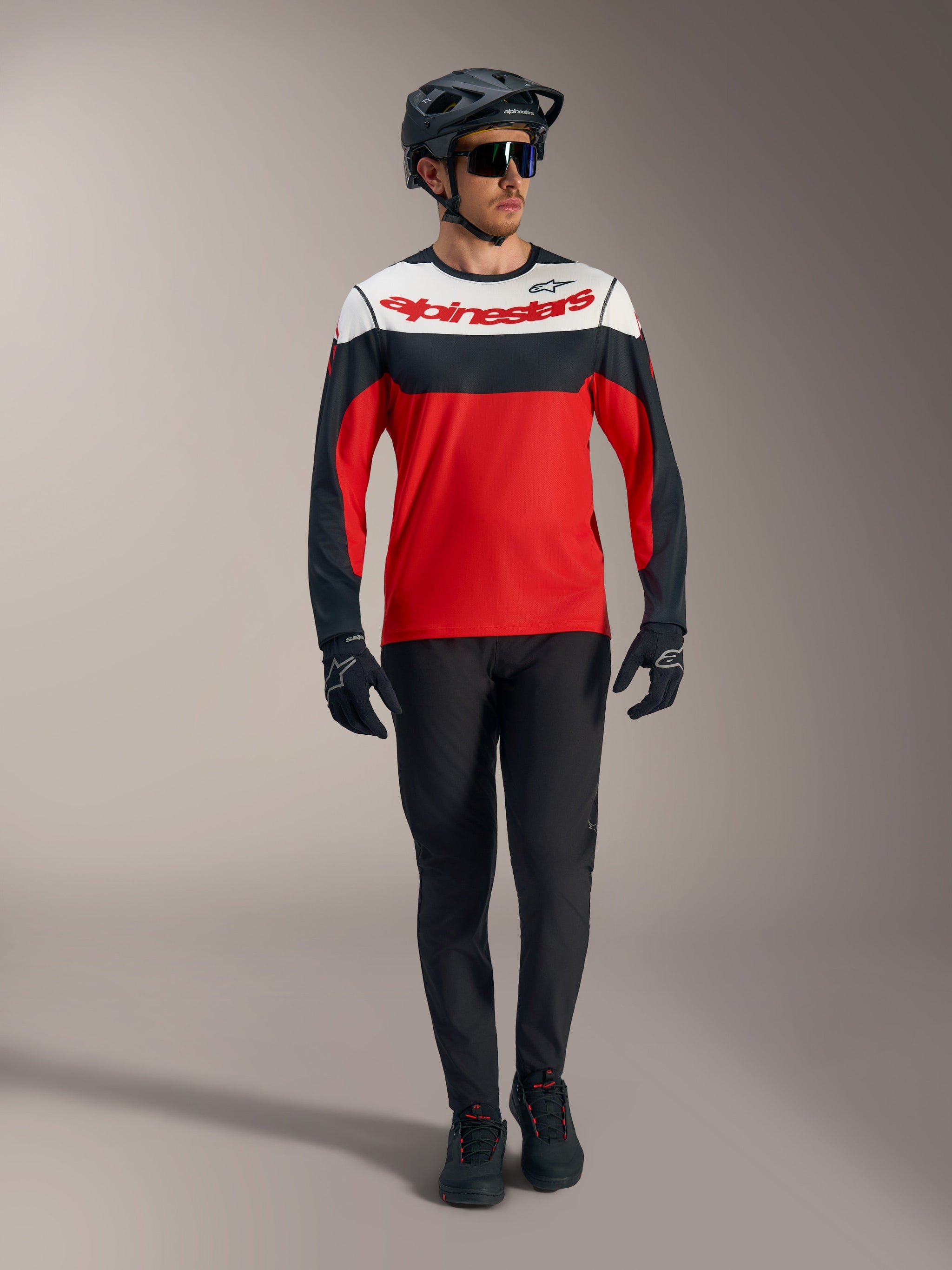 Maglia Alpinestars A-Dura Race rossa a maniche lunghe con pannelli bianchi e neri, pantaloni MTB e attrezzatura da gara.