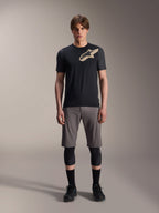 Alpinestars A-Dura Lipan Short Sleeve Jersey, maglia a maniche corte nera con maniche grigio melange e logo Astars color sabbia sul petto, indossata da un modello uomo con pantaloncini da mountain bike grigi e ginocchiere nere, abbigliamento tecnico da MTB