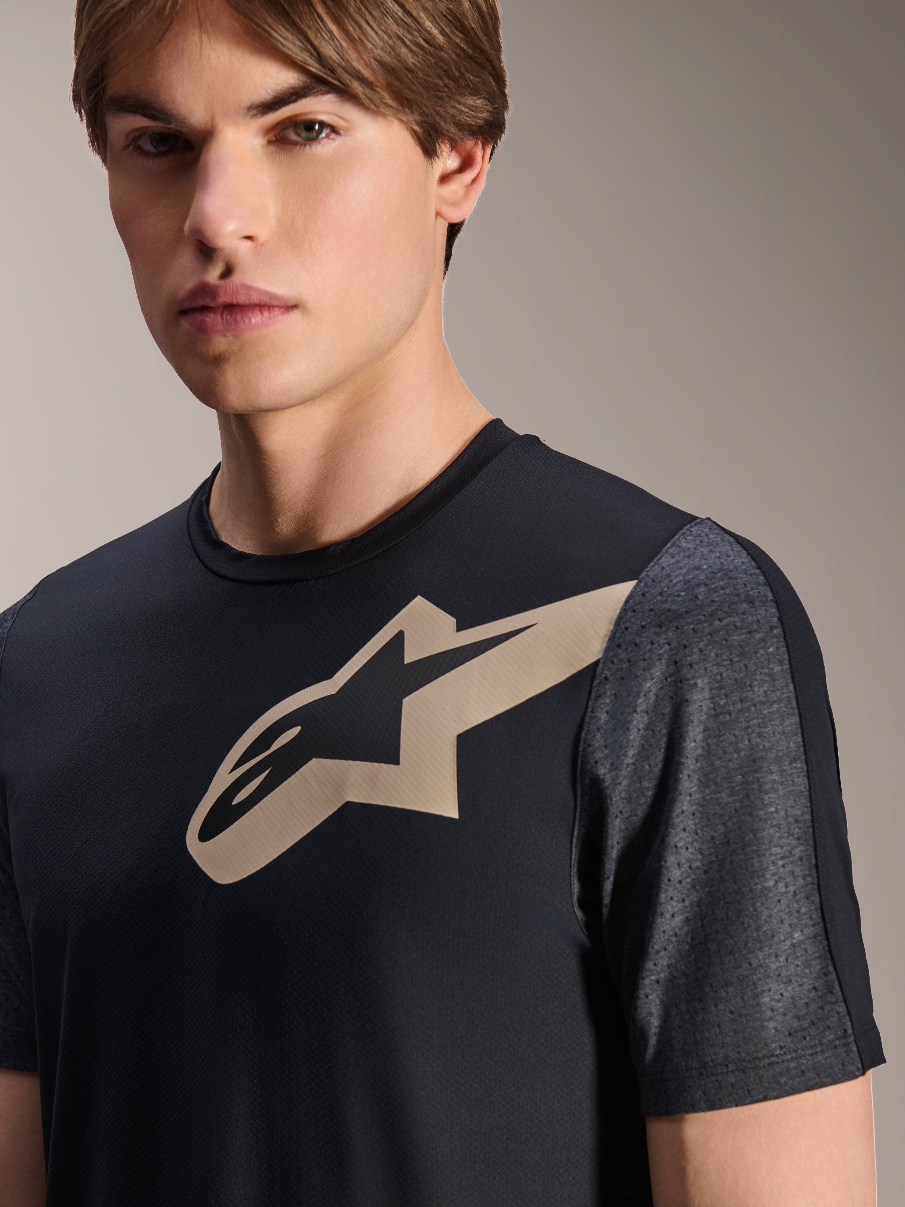 Alpinestars A-Dura Lipan Jersey - a maniche corte, nero, con logo Astars beige sul petto e maniche traforate grigio scuro melange, abbigliamento tecnico per mountain bike