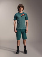 Alpinestars A-Dura Lipan Jersey, maglia da MTB a maniche corte, verde Silver Pine con logo Astars nero e arancione sul petto, abbinata a pantaloncini coordinati e scarpe nere, abbigliamento tecnico da mountain bike