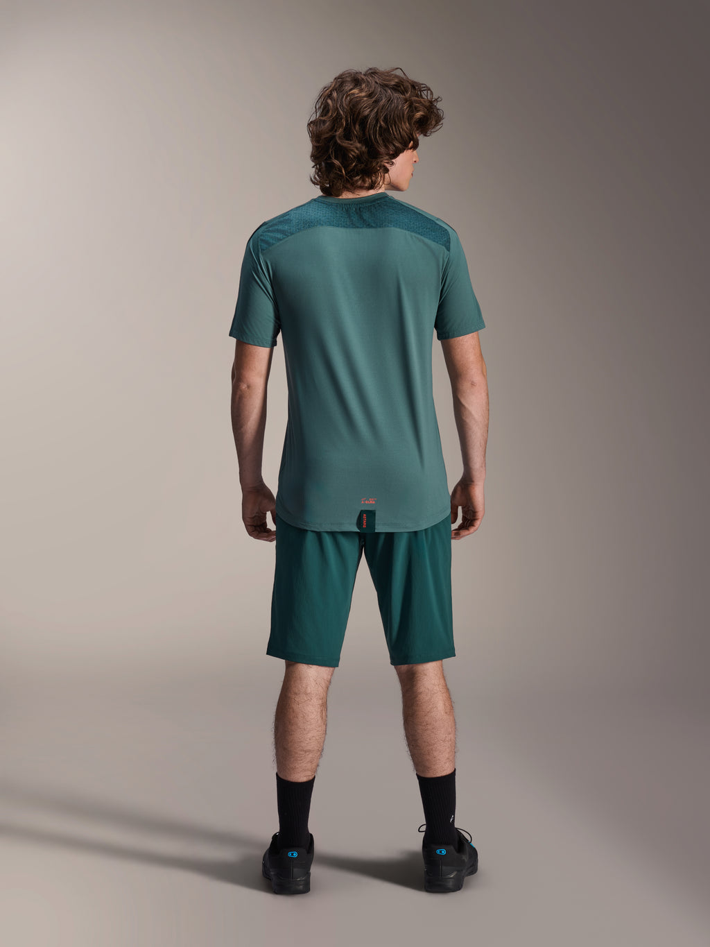 Pantaloncini Alpinestars A-Dura e Maglia A-Dura Lipan SS, verde Dark Pine, vista posteriore su un modello, abbigliamento tecnico per mountain bike con maglia a maniche corte e pantaloncini coordinati, completo da ciclismo off-road