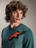 Alpinestars A-Dura Lipan Jersey, maglia MTB a maniche corte, Silver Pine, con prominente logo Astars rosso e nero sul petto, maniche in jacquard testurizzato, ritratto ravvicinato di un modello che indossa abbigliamento tecnico da ciclismo