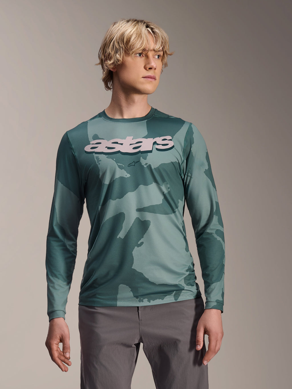 Alpinestars A-Dura Hollow Camo Jersey a maniche lunghe, maglia da MTB, motivo mimetico verde Silver Pine Camo, grande logo astars grigio chiaro sul petto, indossata con pantaloni grigi, abbigliamento da mountain bike ad alte prestazioni