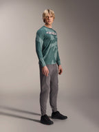 Maglia a maniche lunghe Alpinestars A-Dura Hollow Camo, Silver Pine Camo, indossata da un modello con pantaloni grigi e scarpe nere, con un motivo mimetico verde e un vistoso logo ASTARS bianco sul petto, abbigliamento MTB ad alte prestazioni