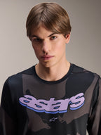 Maglia Alpinestars A-Dura Hollow Camo - Maniche Lunghe, Black Camo con grafica 'astars' viola sul petto, scatto in studio di un modello che indossa abbigliamento MTB, stile casual e tecnico da mountain bike