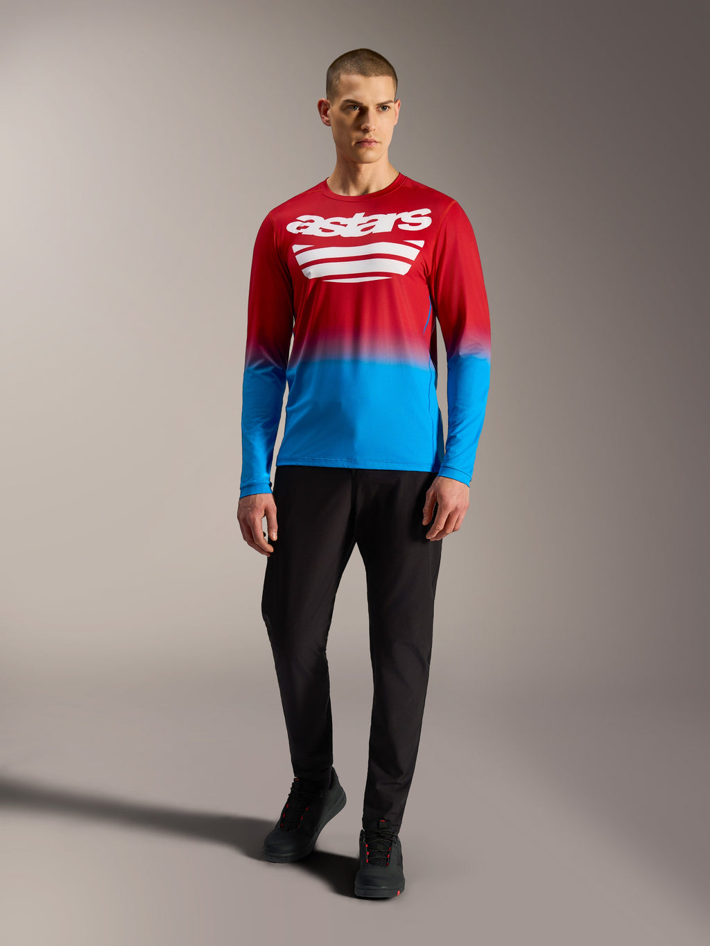Alpinestars A-Dura ASTARS 2.0, maglia MTB a maniche lunghe rossa e blu sfumata con loghi bianchi e pantaloni neri.