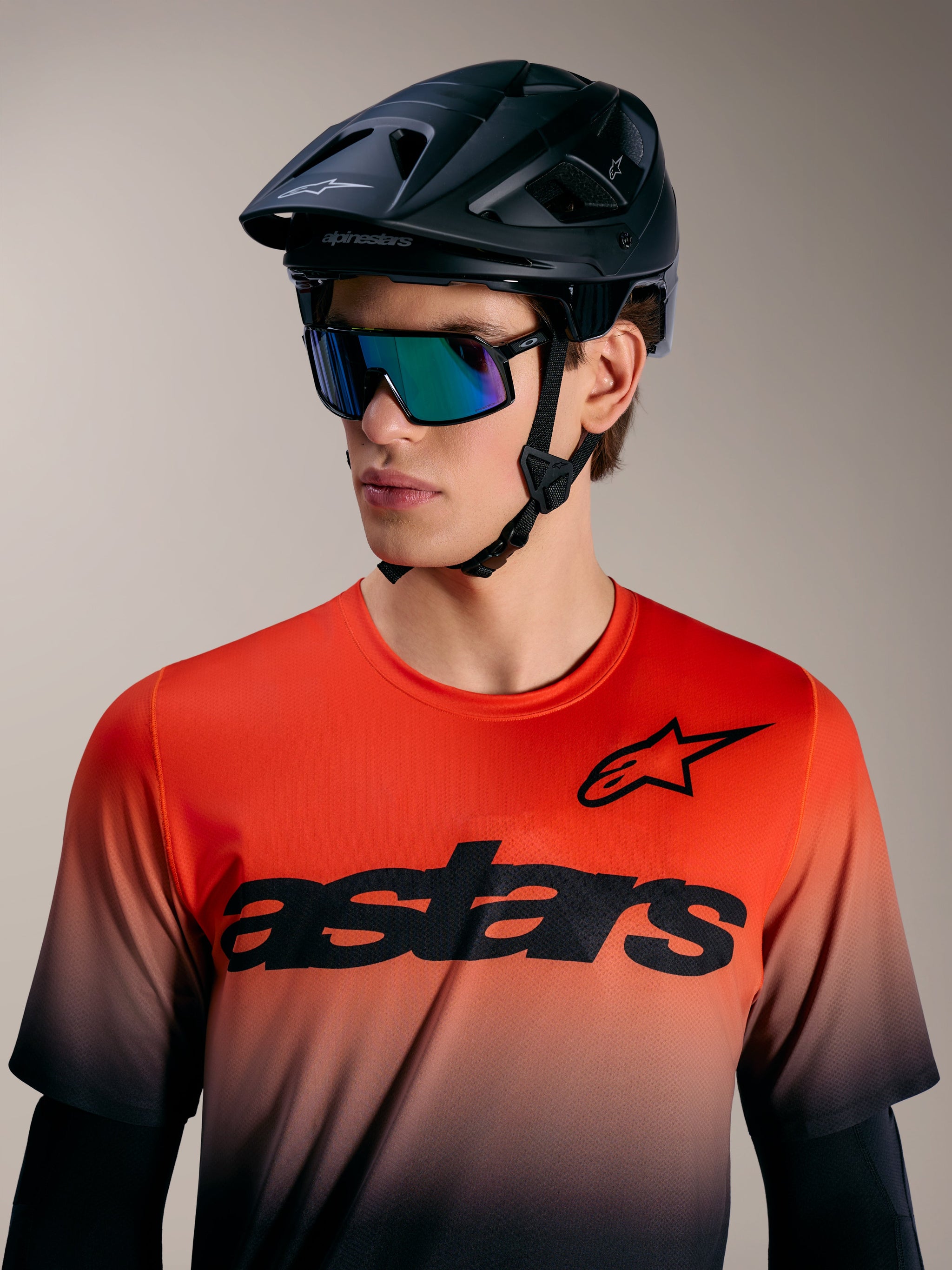 Maglia A-Dura ASTARS 2.0, top MTB sfumato arancione e nero a maniche corte con logo evidente e casco nero.