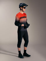 Maglia A-Dura ASTARS 2.0 a maniche corte, sfumatura arancione e nera, con attrezzatura da MTB completa.