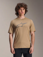 Alpinestars Maglia A-Dura Astar a maniche corte, marrone chiaro, indossata da modello uomo con pantaloni neri, logo a stella Alpinestars grigio sul petto, maglia casual da mountain bike per trail riding