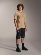 Alpinestars A-Dura Shorts, pantaloncini da mountain bike neri, indossati da un modello con maglia a maniche corte color sabbia e logo Alpinestars, calze nere e scarpe nere, equipaggiamento MTB resistente per il fuori strada