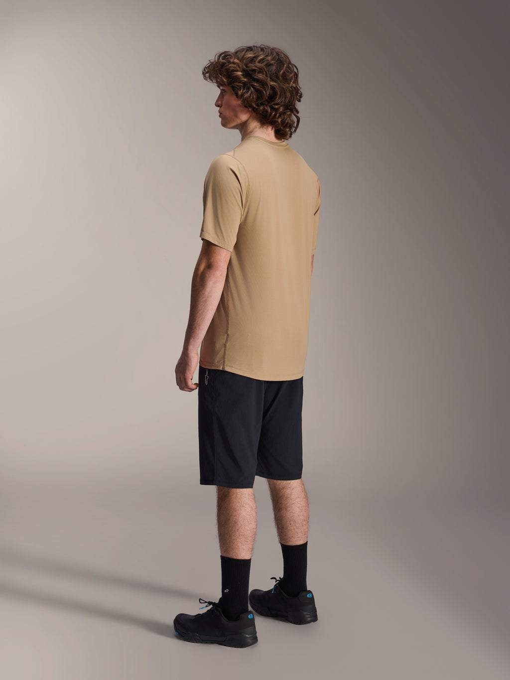 Alpinestars A-Dura Shorts, pantaloncini da mountain bike, nero, abbinati a una maglia a maniche corte A-Dura color sabbia e scarpe da ciclismo nere, con vestibilità regolare e struttura resistente per il ciclismo fuoristrada, vista posteriore laterale