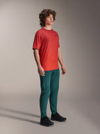 Modello che indossa i pantaloni Alpinestars A-Dura in Dark Pine, abbinati a una maglia a maniche corte A-Dura Rise rossa e scarpe da MTB nere, abbigliamento tecnico da mountain bike in studio