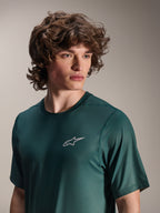 Alpinestars A-Dura Rise Jersey a maniche corte, verde Silver Pine, indossata da un modello, piccolo logo Astars bianco sul petto, tessuto tecnico jacquard, abbigliamento casual per mountain bike