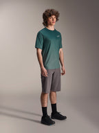 Alpinestars Maglia A-Dura Rise - Manica Corta in Silver Pine, maglia da mountain bike verde indossata da un modello con pantaloncini grigi e sneakers nere, abbigliamento casual per trail riding MTB con un piccolo logo bianco sul petto