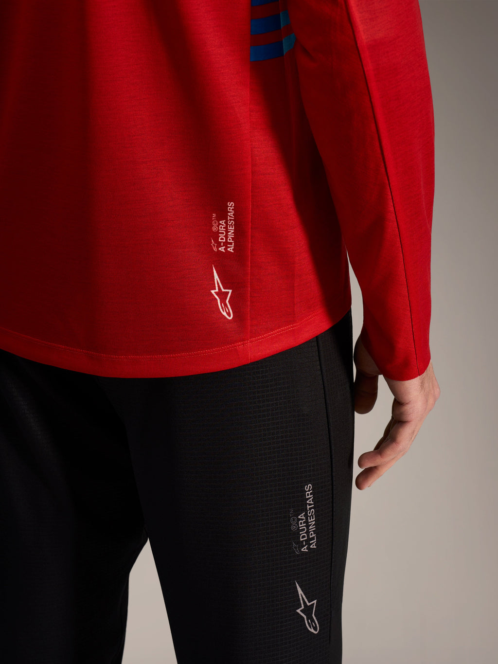 Maglia rossa a maniche lunghe A-Dura Elite 2.0 e pantaloni MTB neri con loghi Alpinestars e tessuto tecnico.