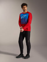 Maglia A-Dura Elite 2.0 rossa a maniche lunghe con pannello blu a righe e logo bianco, abbinata a pantaloni MTB neri.