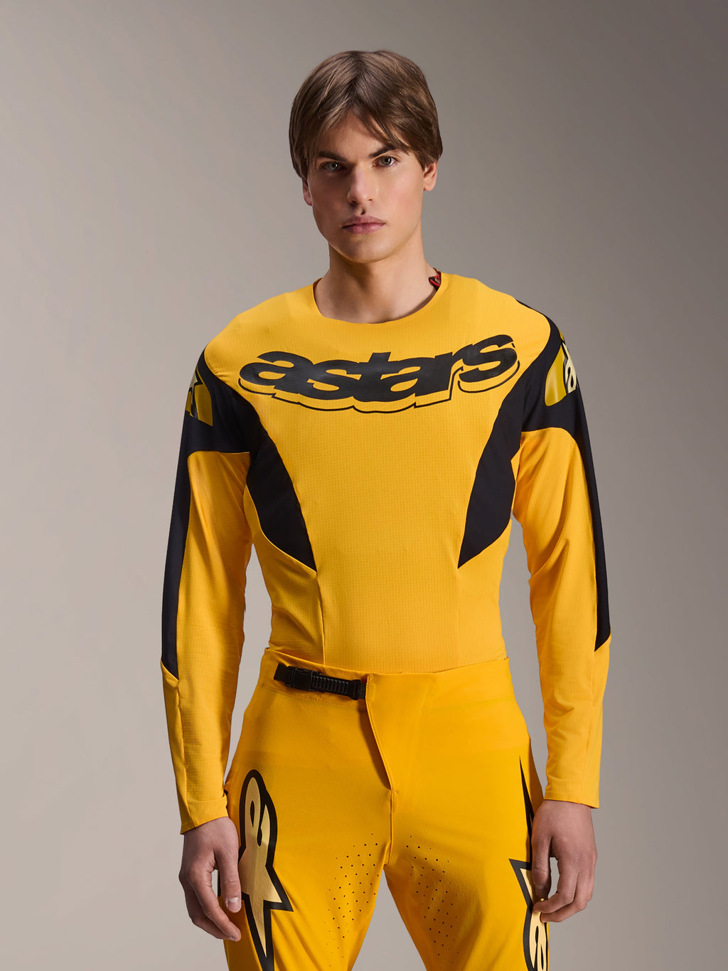 Alpinestars Limited Edition A-Supra Melt Gold Jersey, maglia da MTB a maniche lunghe, giallo scuro con accenti neri, indossata da un modello con pantaloni coordinati, caratterizzata da un grande logo 'astars' nero sul petto e design atletico ad alte prestazioni