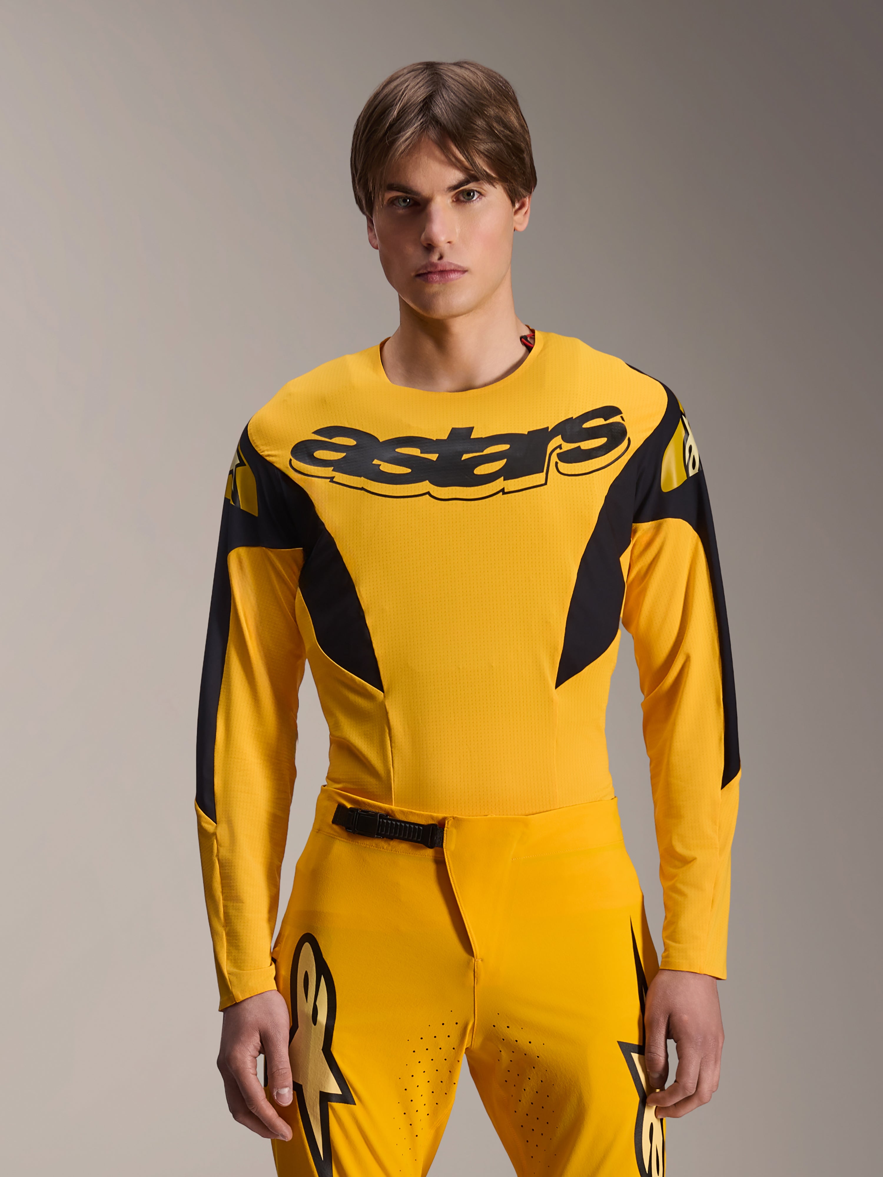 Alpinestars Limited Edition A-Supra Melt Gold Jersey, maglia da MTB a maniche lunghe, giallo scuro con accenti neri, indossata da un modello con pantaloni coordinati, caratterizzata da un grande logo 'astars' nero sul petto e design atletico ad alte prestazioni