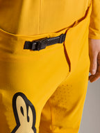 Alpinestars Limited Edition A-Supra Melt Gold Pants, pantaloni da mountain bike, giallo scuro, primo piano del sistema di chiusura a cricchetto nero sulla fascia in vita, con perforazioni laser sull'interno coscia per la ventilazione