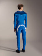 Modello maschile visto dal retro che indossa la maglia a maniche lunghe Alpinestars A-Supra Melt in blu, abbinata a pantaloni tecnici blu coordinati con un grande logo Alpinestars bianco sul retro, kit completo da gara MTB.