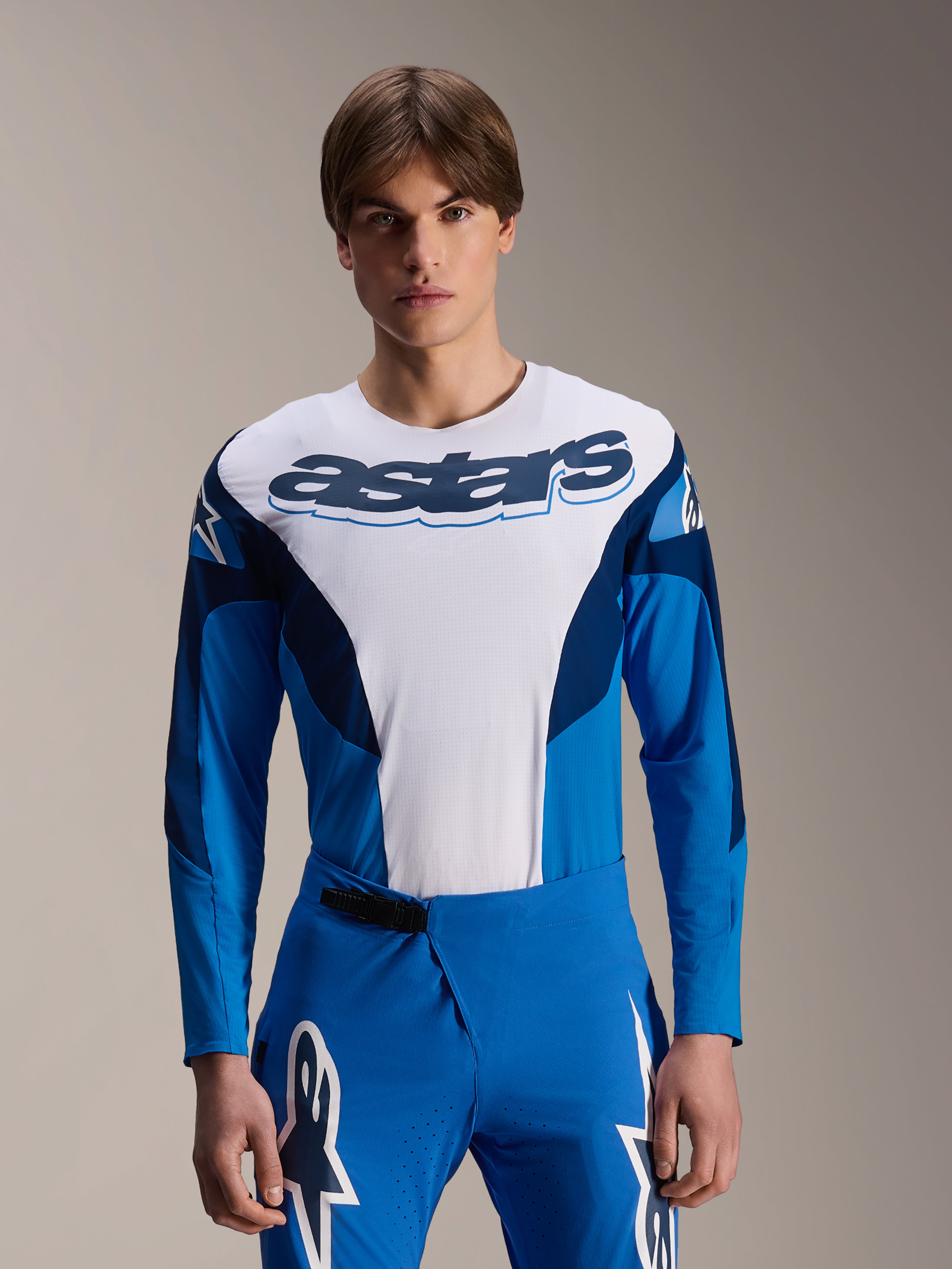 Alpinestars A-Supra Melt Jersey a maniche lunghe, maglia da MTB blu e bianca con vistoso marchio astars sul petto, maniche blu scuro, indossata con pantaloni da corsa blu coordinati con loghi a stella bianchi, abbigliamento da mountain bike ad alte prestazioni
