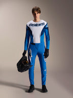 Modello con kit MTB Alpinestars A-Supra Melt, maglia a maniche lunghe bianca e blu con scritta "astars", pantaloni A-Supra Melt blu con logo bianco, casco integrale nero, guanti e scarpe neri, abbigliamento coordinato per ciclismo off-road