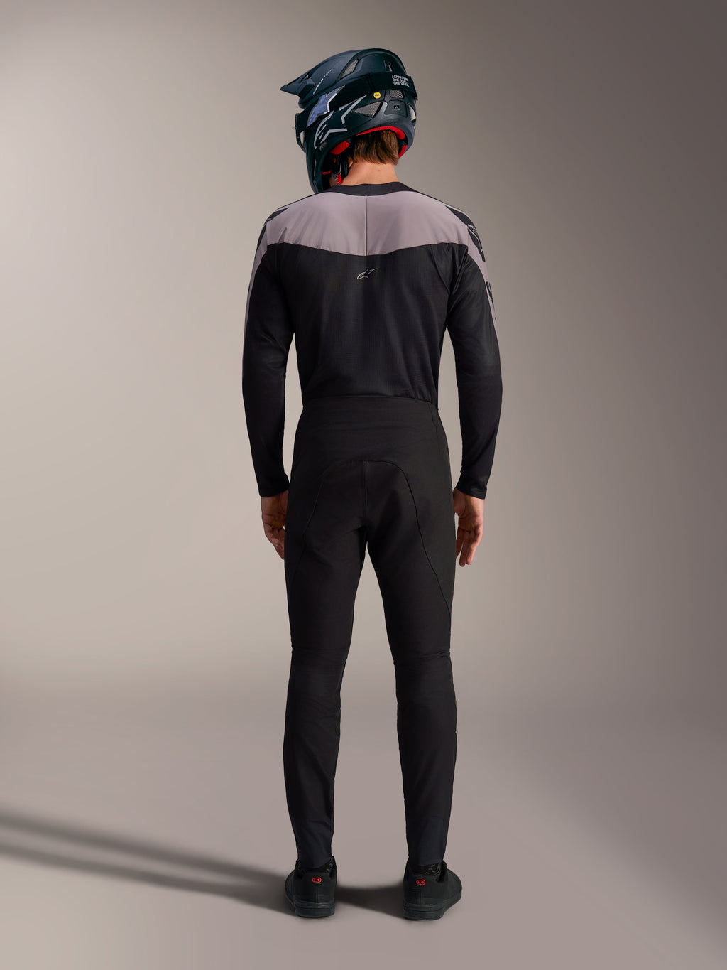 Kit MTB Alpinestars A-Supra Elite nero con maglia, pantaloni tecnici e casco integrale, vista posteriore.