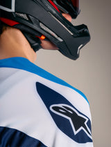 Maglia A-Supra Elite Alpinestars azzurra e bianca con logo Astars sulla spalla e casco da MTB nero.