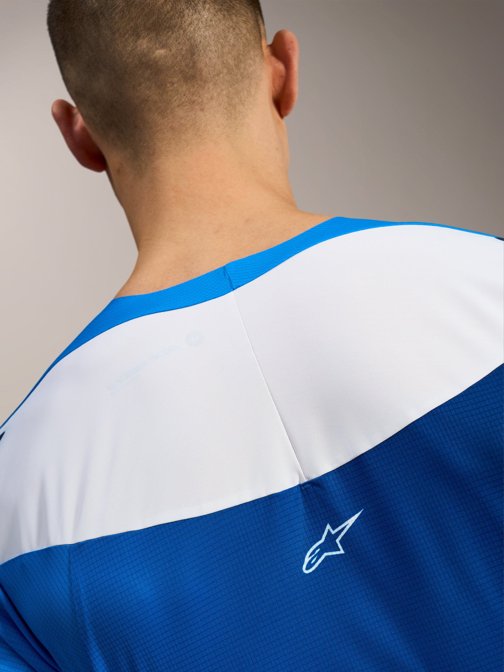 Maglia Alpinestars A-Supra Elite, dettaglio retro in tessuto microforato blu e bianco con logo ASTARS bianco.