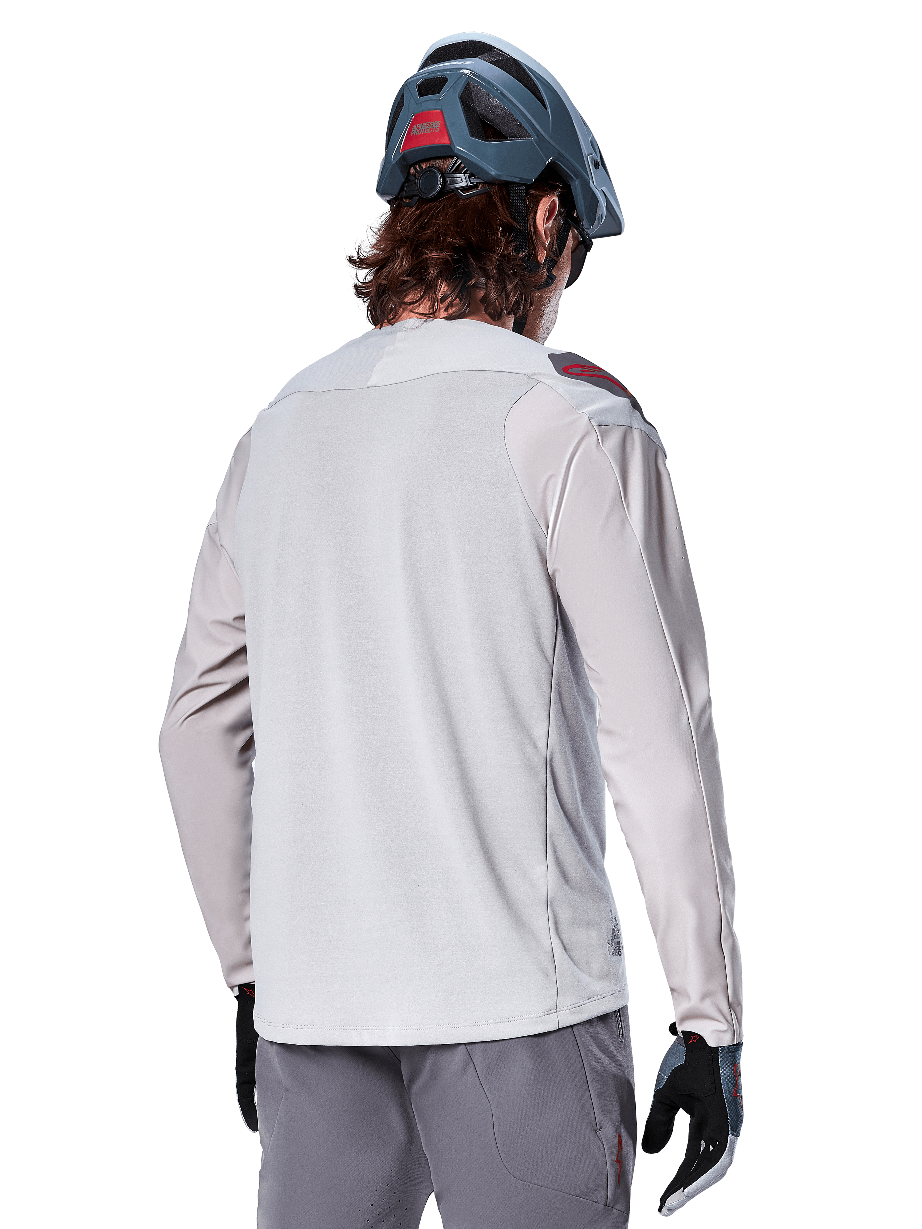 Alpinestars A-Aria Polartec Switch Long Sleeve Jersey, Grigio Chiaro, vista dal retro su un pilota, indossata con casco blu da mountain bike e pantaloni grigi, abbigliamento tecnico da mountain bike per percorsi off-road