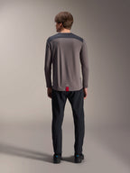 Maglia a maniche lunghe Alpinestars A-Dura Insert Astar in grigio scuro, vista posteriore, con pannelli sulle spalle color antracite e un'etichetta rossa sull'orlo, indossata con pantaloni e scarpe neri, abbigliamento tecnico per mountain bike