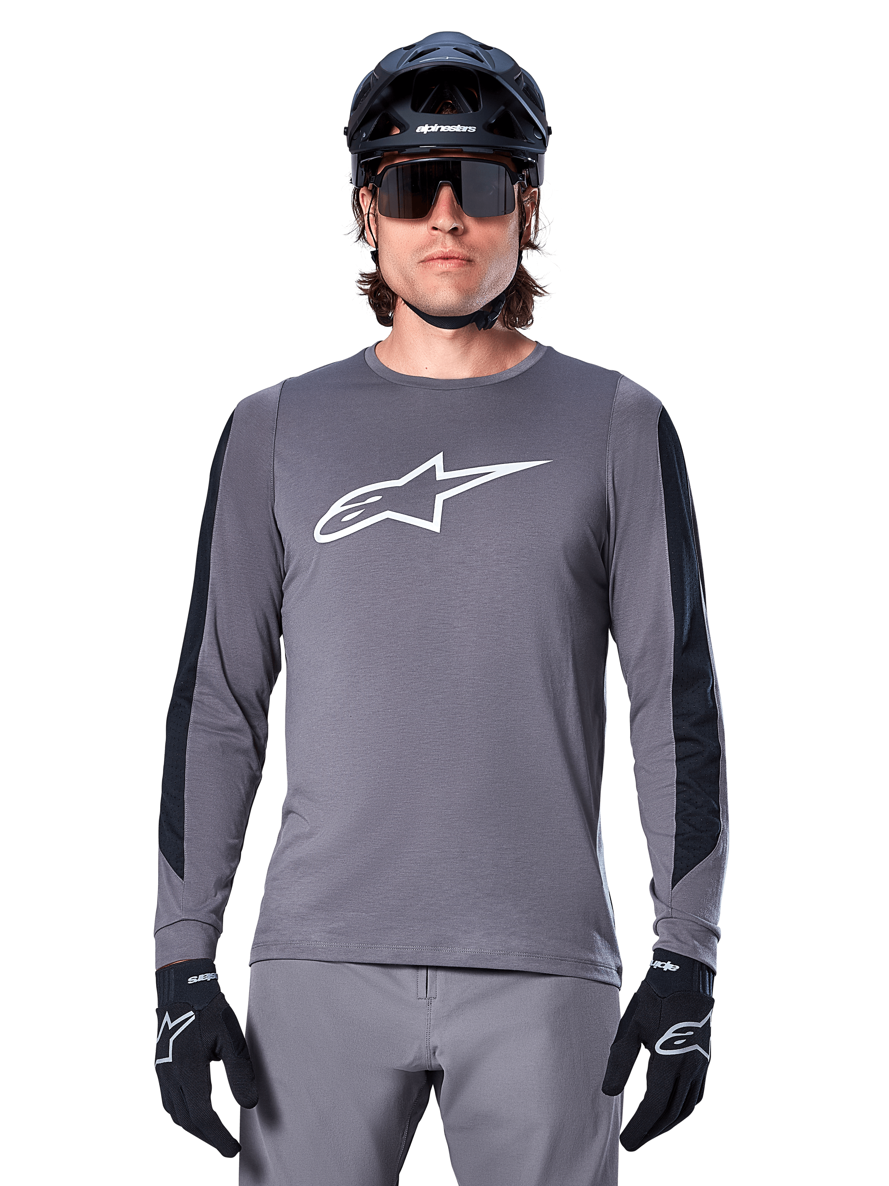 Alpinestars A-Dura Dri Astar Long Sleeve Jersey, maglia a maniche lunghe grigio scuro, con un grande logo Astar bianco sul petto e pannelli in mesh neri sulle braccia, indossata da un ciclista con casco da mountain bike nero e occhiali tecnici, abbigliamento da ciclismo MTB