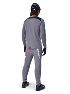 Maglia Alpinestars A-Dura Dri Astar - Maniche Lunghe, grigio scuro, vista posteriore del ciclista con pantaloni abbinati e casco nero, presenta pannelli neri sulle spalle e una piccola etichetta rossa sull'orlo, abbigliamento tecnico da ciclismo fuoristrada