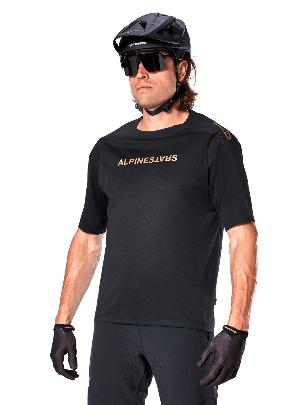 Alpinestars A-Aria Polartec Switch Jersey a maniche corte, maglia da mountain bike nera con logo Alpinestars color oro, indossata con casco nero, occhiali da sole e guanti, abbigliamento tecnico da MTB