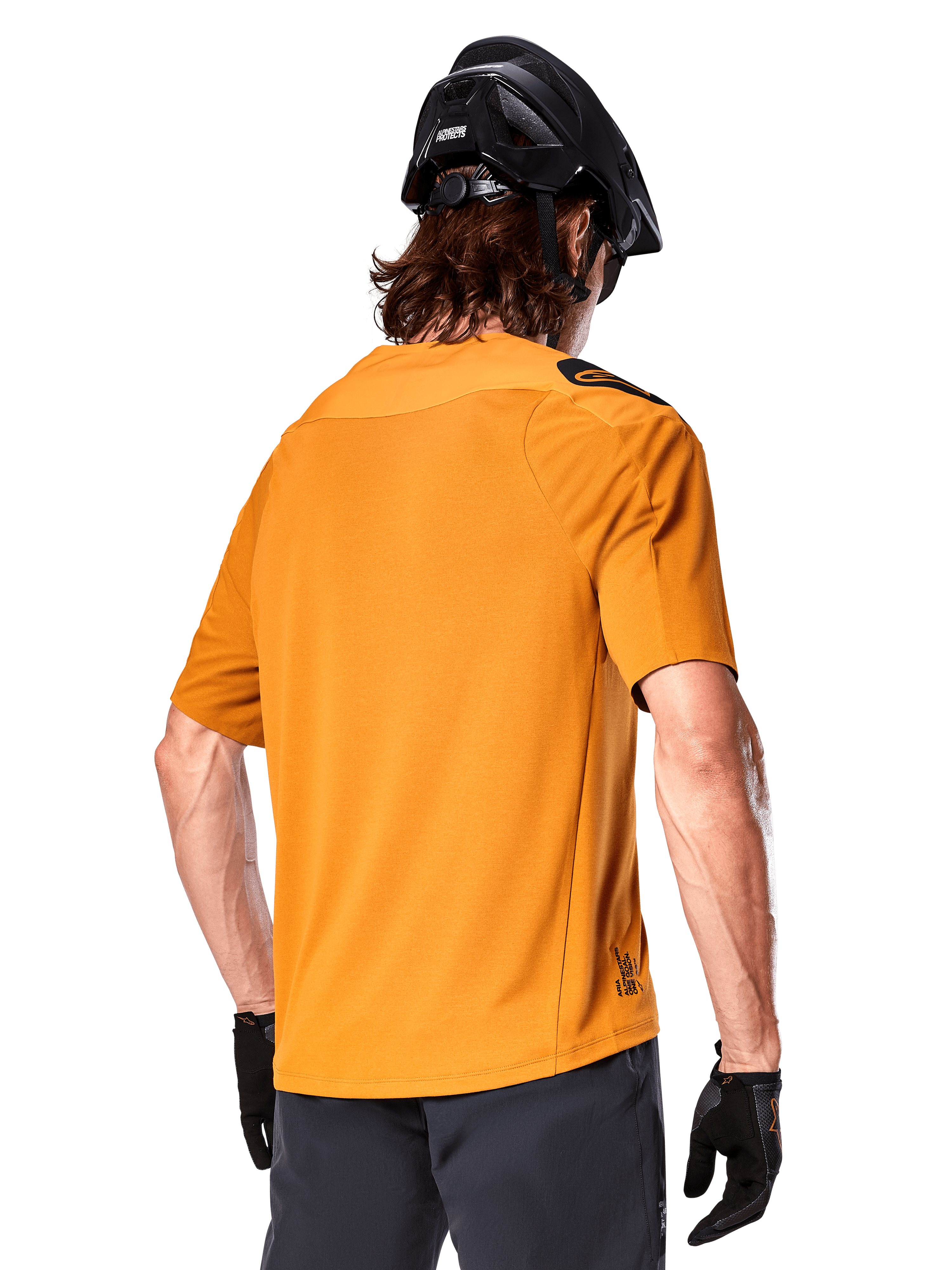 Maglia Alpinestars A-Aria Polartec Switch, maglia da MTB a maniche corte, oro scuro, vista posteriore con vestibilità performante, indossata con casco nero e pantaloncini grigi, abbigliamento da trail riding resistente e traspirante