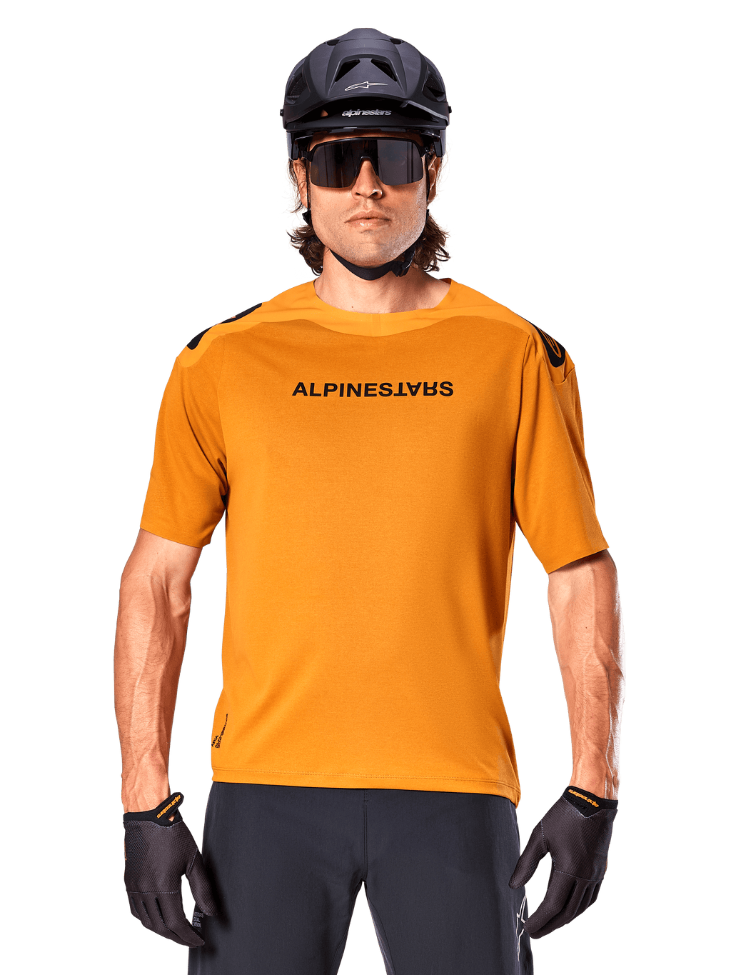 Maglia a maniche corte Alpinestars A-Aria Polartec Switch, oro scuro, ciclista di mountain bike con casco nero e occhiali da sole, abbigliamento tecnico da ciclismo per percorsi MTB