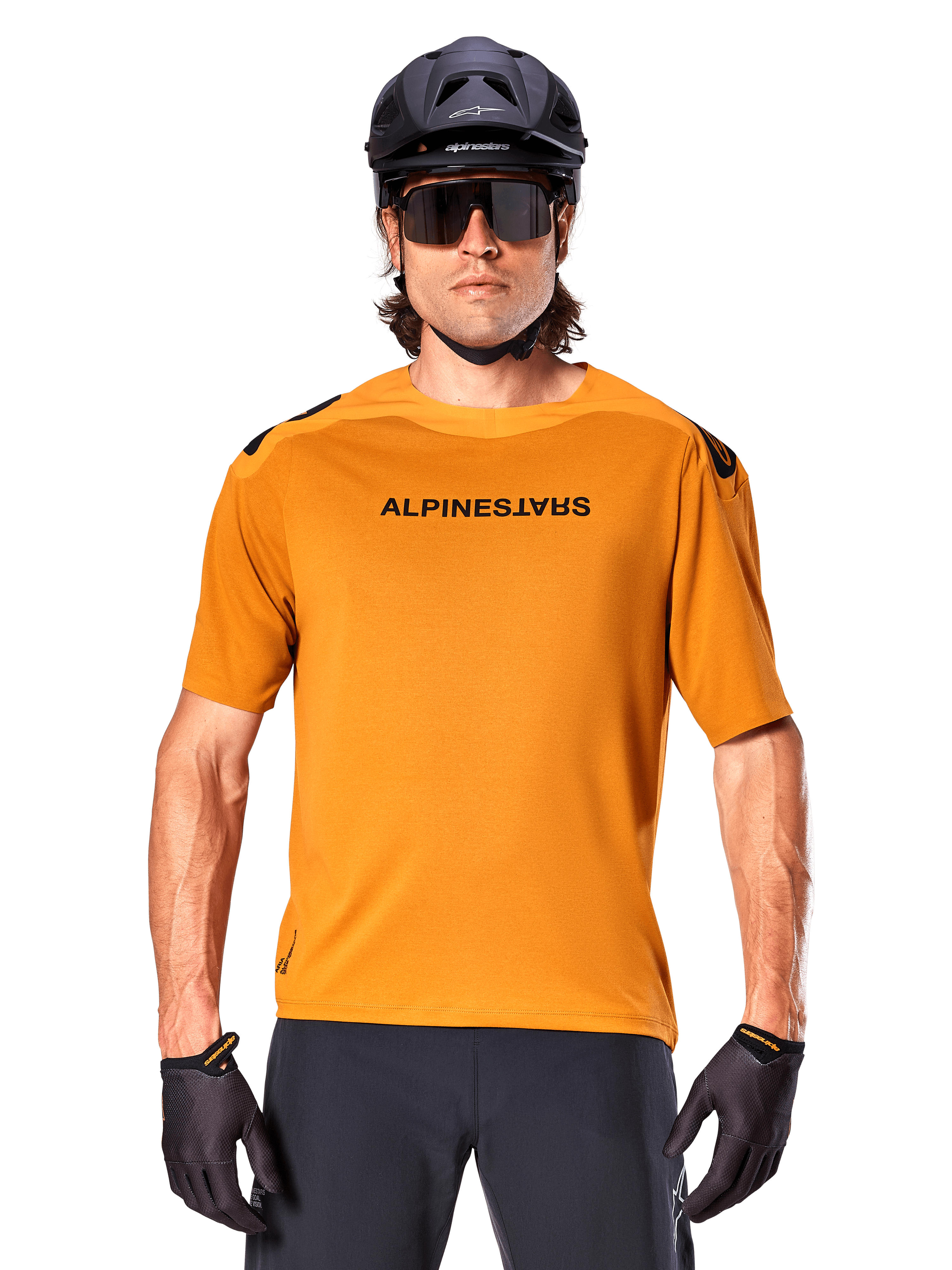 Maglia a maniche corte Alpinestars A-Aria Polartec Switch, oro scuro, ciclista di mountain bike con casco nero e occhiali da sole, abbigliamento tecnico da ciclismo per percorsi MTB