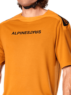Alpinestars A-Aria Polartec Switch Jersey, maglia MTB a maniche corte, oro scuro, con logo Alpinestars nero specchiato sul petto, tessuto tecnico per il trail riding in mountain bike
