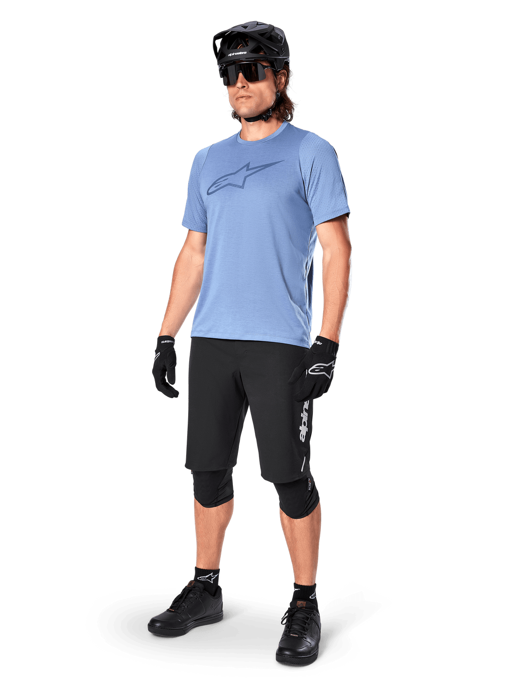 Pilota uomo che indossa la maglia a maniche corte Alpinestars A-Dura Dri Astar in Infinity Blue, abbinata a pantaloncini da MTB neri, casco nero, occhiali da sole, ginocchiere e guanti, outfit completo da mountain bike