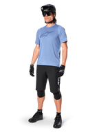 Pilota uomo che indossa la maglia a maniche corte Alpinestars A-Dura Dri Astar in Infinity Blue, abbinata a pantaloncini da MTB neri, casco nero, occhiali da sole, ginocchiere e guanti, outfit completo da mountain bike