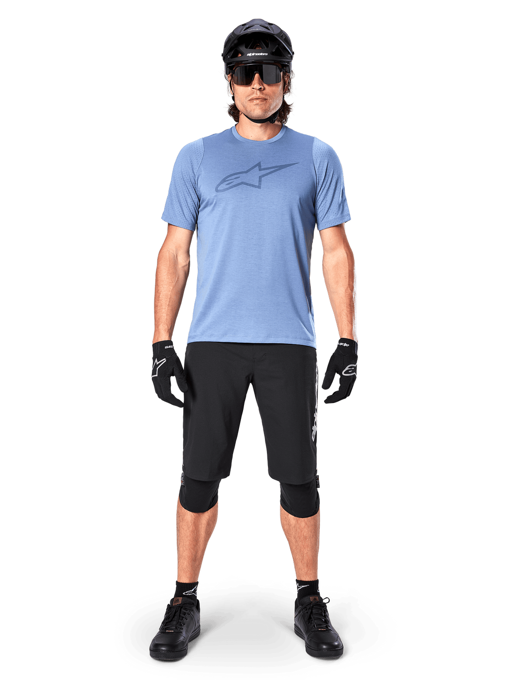 Rider di mountain bike che indossa la maglia a maniche corte Alpinestars A-Dura Dri Astar in Infinity Blue, con un prominente logo Astars sul petto, coordinata con pantaloncini MTB neri, casco nero, occhiali da sole e attrezzatura protettiva per il fuoristrada