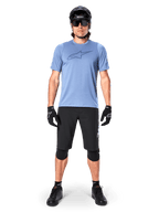 Rider di mountain bike che indossa la maglia a maniche corte Alpinestars A-Dura Dri Astar in Infinity Blue, con un prominente logo Astars sul petto, coordinata con pantaloncini MTB neri, casco nero, occhiali da sole e attrezzatura protettiva per il fuoristrada
