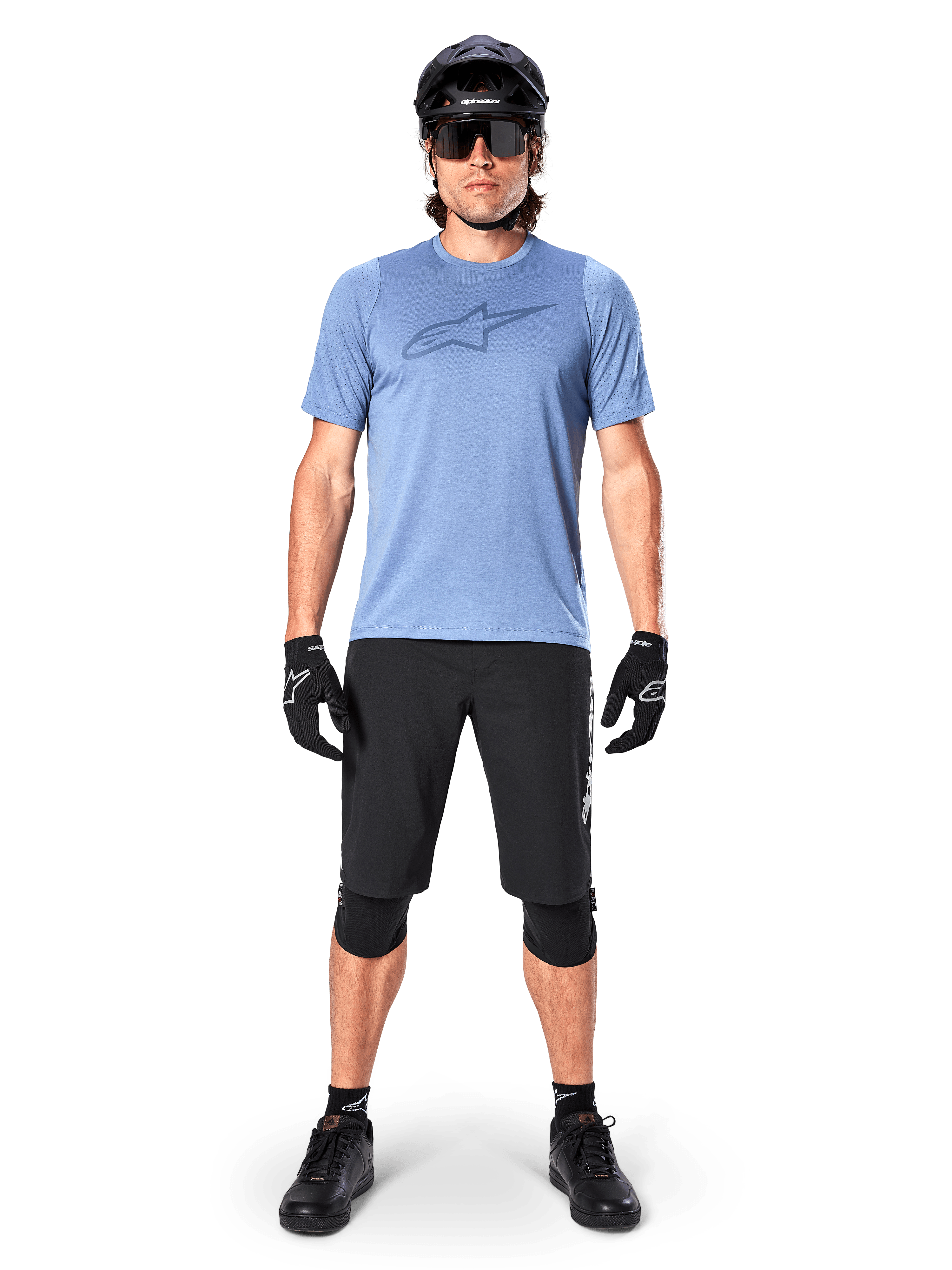 Rider di mountain bike che indossa la maglia a maniche corte Alpinestars A-Dura Dri Astar in Infinity Blue, con un prominente logo Astars sul petto, coordinata con pantaloncini MTB neri, casco nero, occhiali da sole e attrezzatura protettiva per il fuoristrada