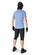 Alpinestars Maglia A-Dura Dri Astar a maniche corte, Infinity Blue, vista posteriore, abbinata a pantaloncini da mountain bike neri e casco, abbigliamento tecnico da ciclismo con tessuto traspirante e coda più lunga