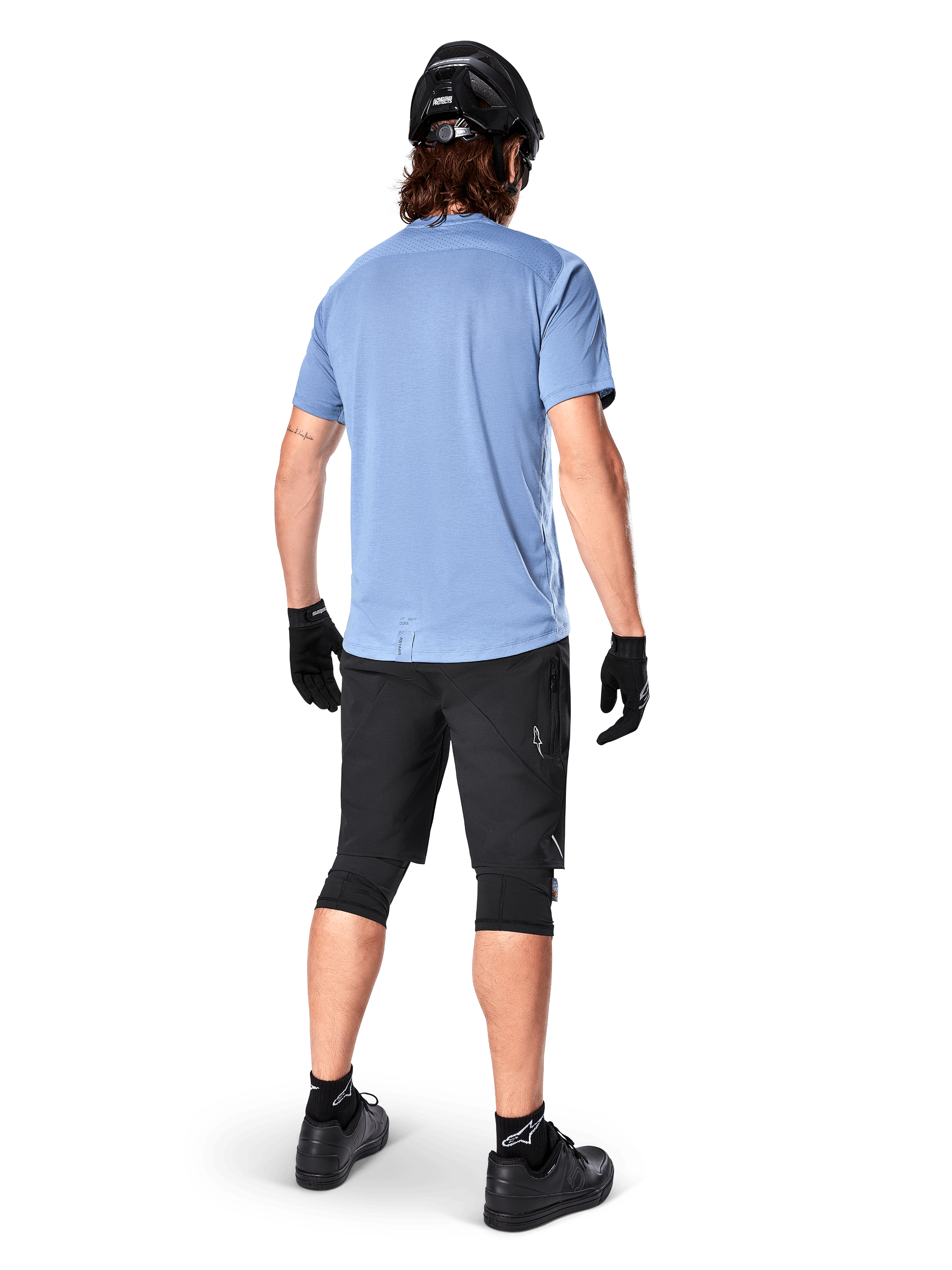 Alpinestars Maglia A-Dura Dri Astar a maniche corte, Infinity Blue, vista posteriore, abbinata a pantaloncini da mountain bike neri e casco, abbigliamento tecnico da ciclismo con tessuto traspirante e coda più lunga