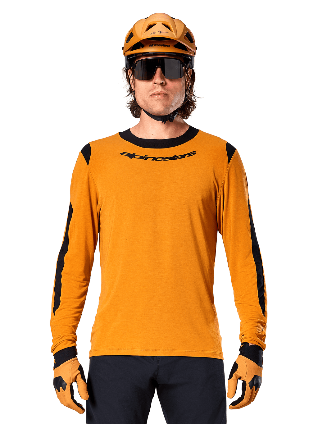 Modello che indossa la maglia a maniche lunghe Alpinestars A-Dura Dri Wool in Dark Gold, coordinata con casco da MTB e guanti oro abbinati, pannelli in rete nera su spalle e maniche, marchio Alpinestars nero sul petto, occhiali da sole e pantaloni scuri, abbigliamento tecnico da mountain bike